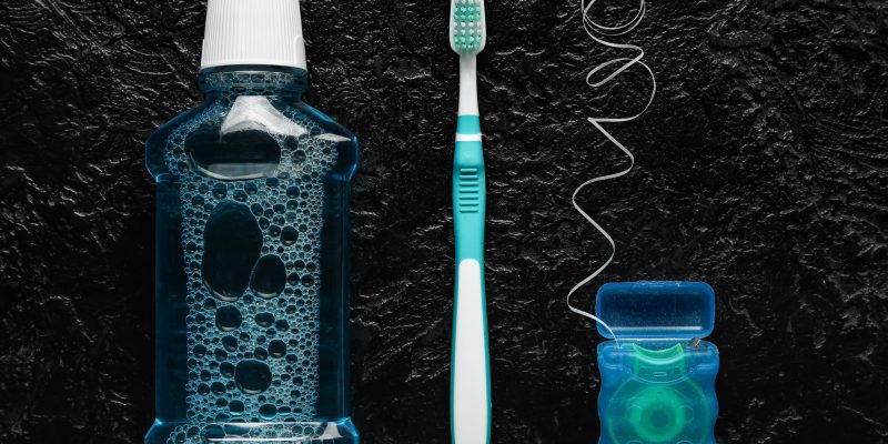 Dental floss with tooth brush and rinse on dark background